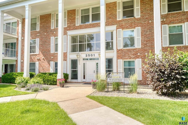 doorway to property with a balcony and a yard