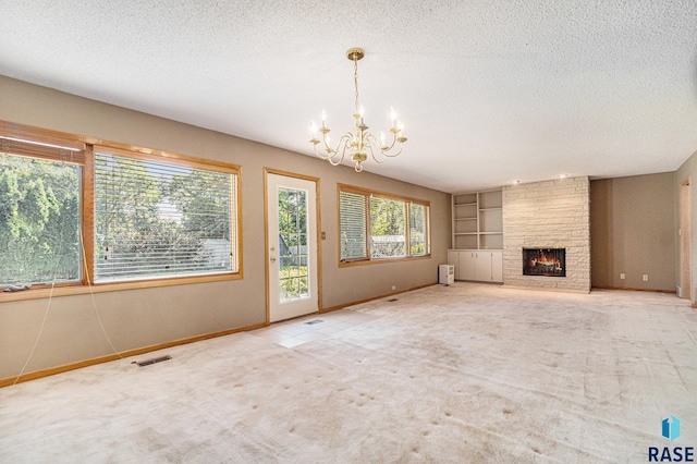 unfurnished living room with a brick fireplace, a notable chandelier, carpet, and a textured ceiling