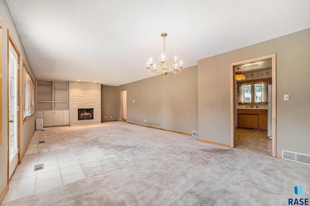 unfurnished living room featuring an inviting chandelier, a textured ceiling, light tile patterned floors, and a fireplace