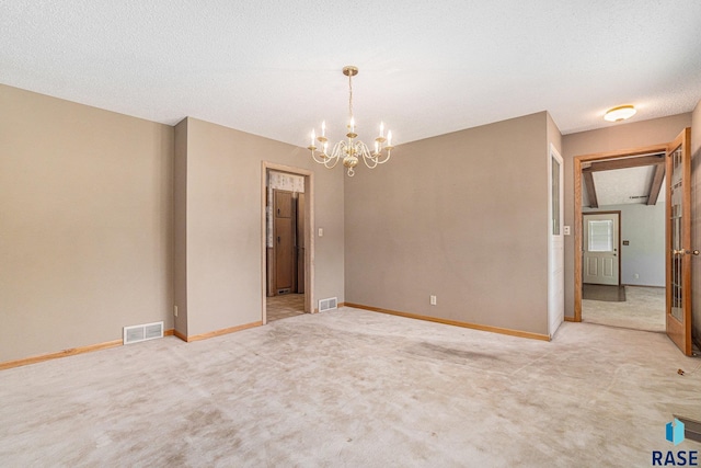 carpeted empty room with a textured ceiling and a notable chandelier