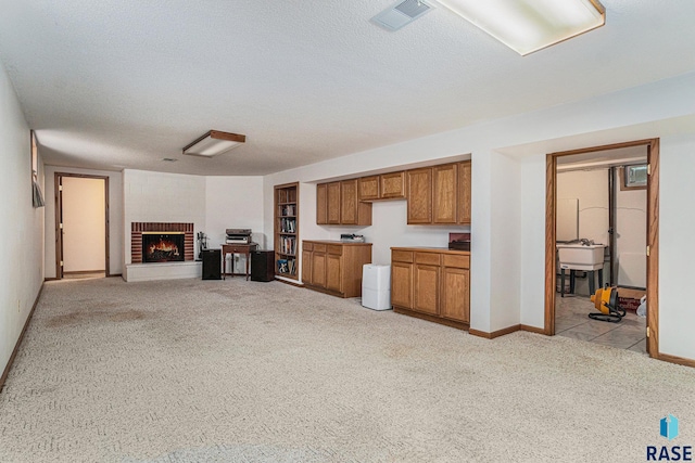 kitchen featuring light carpet, a brick fireplace, a textured ceiling, and sink