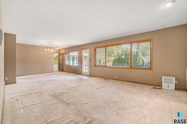 unfurnished room featuring light colored carpet, an inviting chandelier, and a textured ceiling