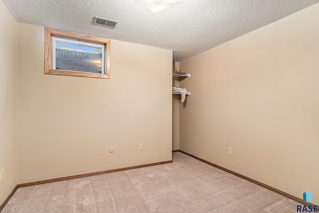 unfurnished room featuring a textured ceiling and light carpet