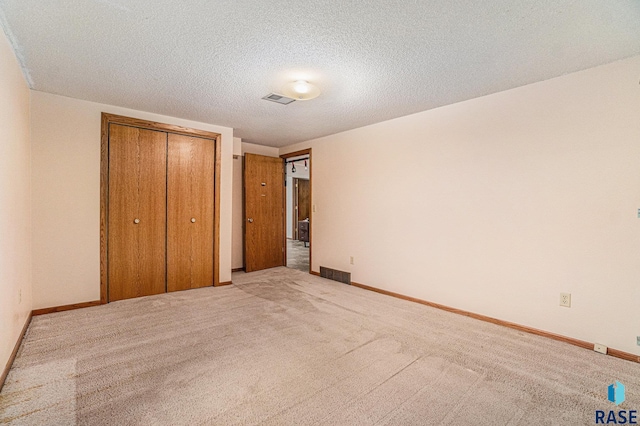 unfurnished bedroom with a closet, light colored carpet, and a textured ceiling