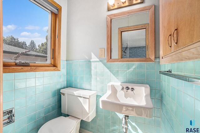 bathroom featuring sink, tile walls, and toilet