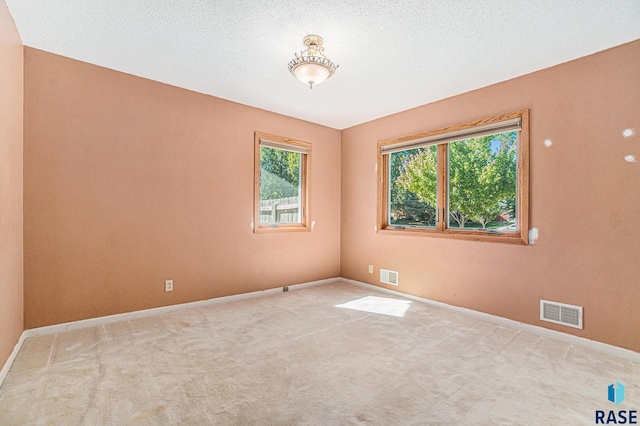 carpeted empty room featuring a textured ceiling