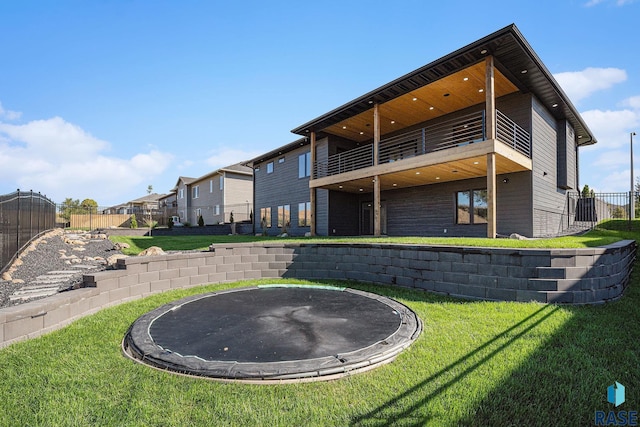 313 Red Spruce Ave, Sioux Falls, SD 57110 - rear view of property with a trampoline, a yard, a balcony, and fence