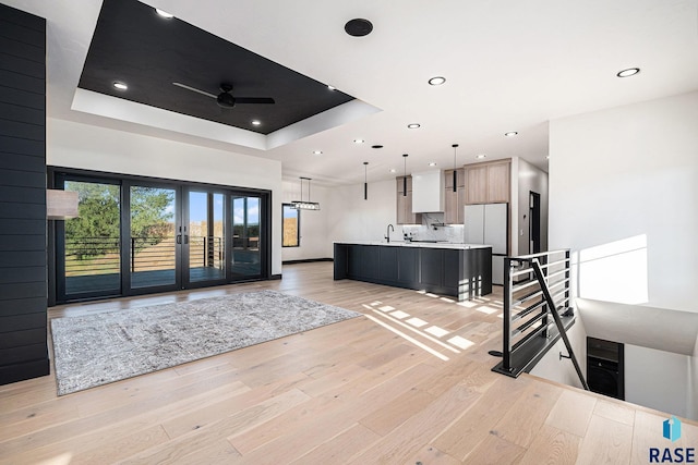 313 Red Spruce Ave, Sioux Falls, SD 57110 - kitchen with open floor plan, light countertops, ceiling fan, a tray ceiling, and light wood-style flooring