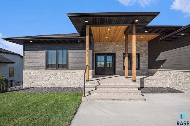 313 Red Spruce Ave, Sioux Falls, SD 57110 - property entrance featuring french doors, stone siding, covered porch, and roof with shingles