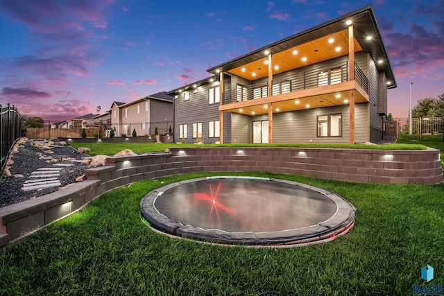 313 Red Spruce Ave, Sioux Falls, SD 57110 - rear view of house featuring a trampoline, a balcony, fence, and a lawn