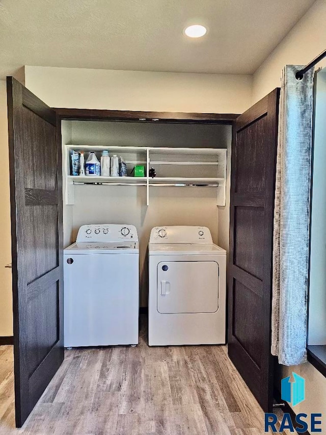 laundry room featuring independent washer and dryer, a textured ceiling, and light wood-type flooring