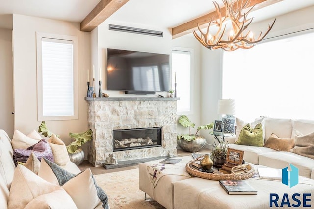 living room with a fireplace, beam ceiling, a chandelier, and plenty of natural light