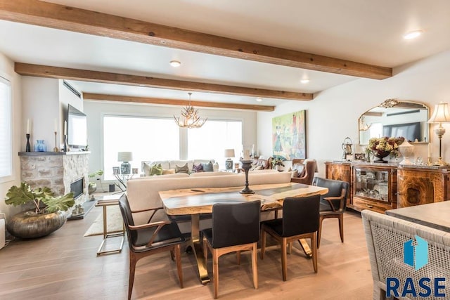 dining area with a stone fireplace, light hardwood / wood-style flooring, and beamed ceiling