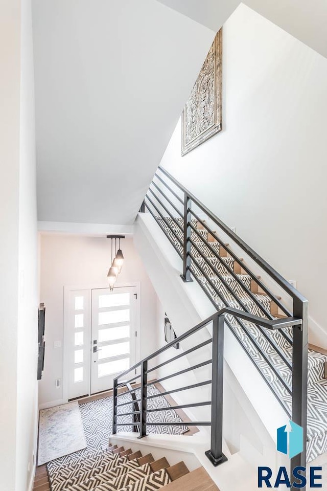 staircase with a towering ceiling and hardwood / wood-style floors