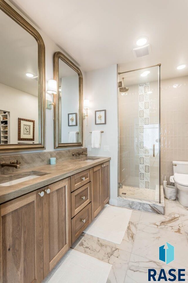 bathroom featuring a shower with door, vanity, and toilet