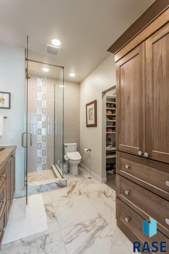 bathroom with vanity, a shower with shower door, and toilet