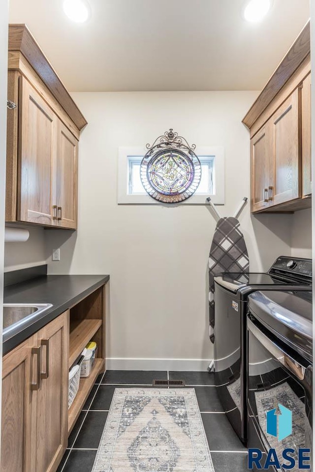 washroom with cabinets, dark tile patterned flooring, separate washer and dryer, and sink