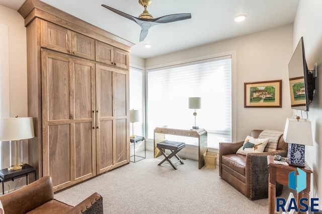 living area featuring ceiling fan and light colored carpet