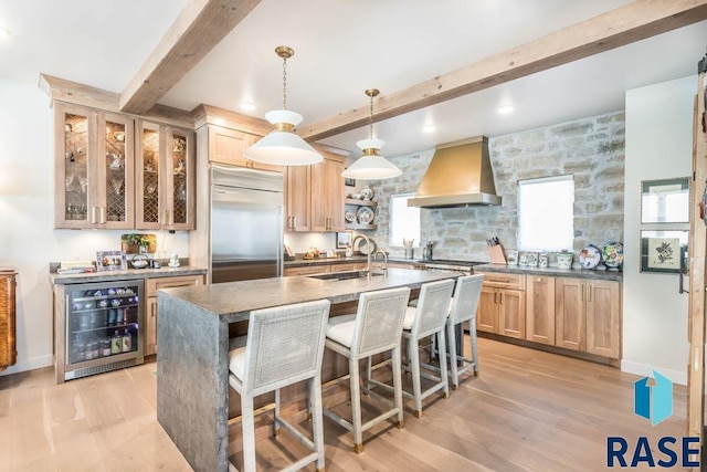 kitchen with light hardwood / wood-style floors, wine cooler, built in fridge, custom exhaust hood, and sink