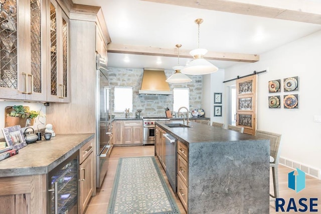 kitchen with wine cooler, sink, appliances with stainless steel finishes, custom range hood, and a barn door