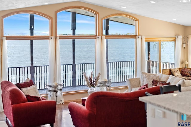 living room featuring a textured ceiling, lofted ceiling, a water view, and hardwood / wood-style flooring