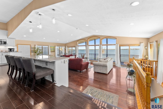 interior space with light stone countertops, a healthy amount of sunlight, a water view, and white cabinetry