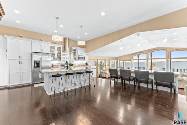 kitchen with a water view, white cabinetry, stainless steel appliances, decorative light fixtures, and dark hardwood / wood-style floors