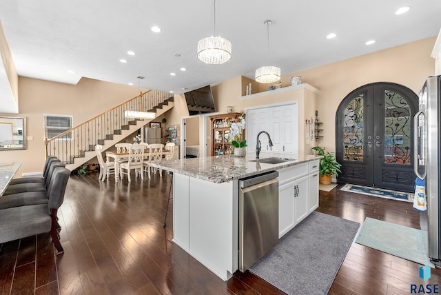 kitchen with sink, an island with sink, hanging light fixtures, an inviting chandelier, and stainless steel appliances