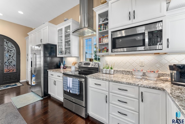 kitchen with appliances with stainless steel finishes, wall chimney exhaust hood, dark hardwood / wood-style flooring, and white cabinetry