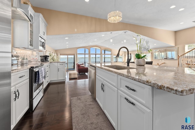 kitchen with appliances with stainless steel finishes, a center island with sink, white cabinetry, and sink