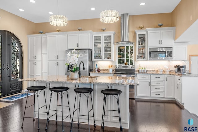 kitchen with stainless steel appliances, a chandelier, hanging light fixtures, and ventilation hood