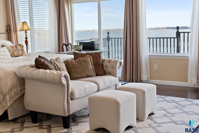 bedroom featuring light wood-type flooring, multiple windows, and a water view