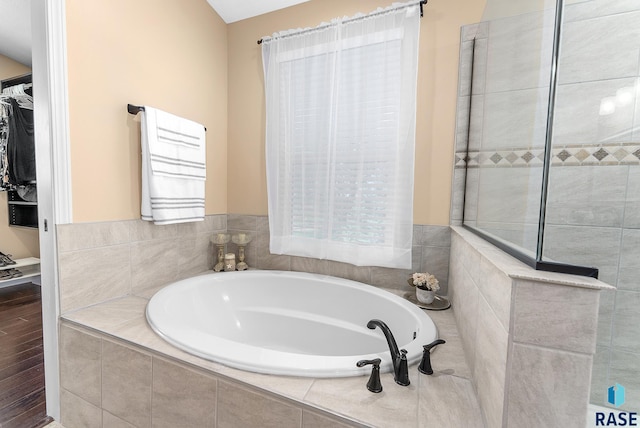 bathroom with tiled tub and hardwood / wood-style flooring