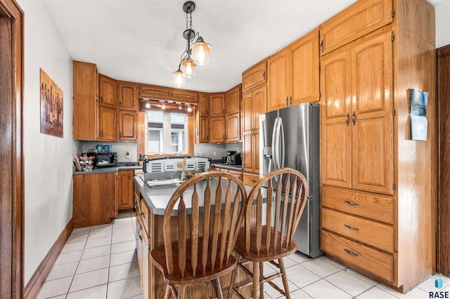 kitchen featuring pendant lighting, light tile patterned floors, stainless steel fridge with ice dispenser, and a center island