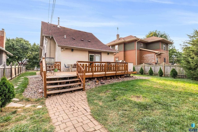 rear view of house featuring a lawn and a deck