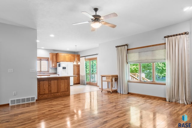 unfurnished living room featuring light wood-style flooring, plenty of natural light, visible vents, and baseboards