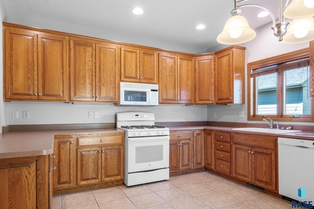 kitchen with white appliances, brown cabinetry, and a sink