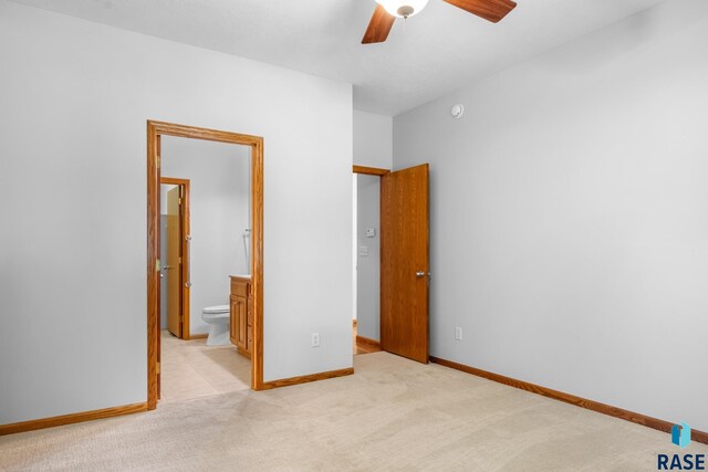 unfurnished bedroom featuring light carpet, ceiling fan, ensuite bath, and baseboards