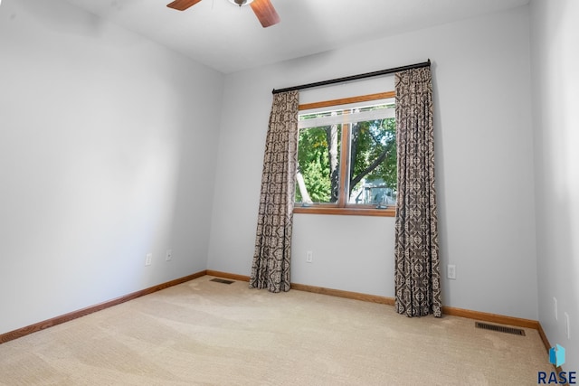 spare room with ceiling fan, carpet floors, visible vents, and baseboards