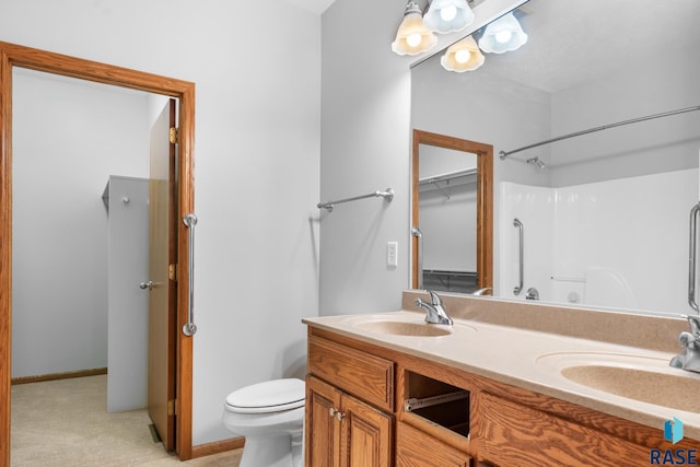 bathroom with a shower, a sink, toilet, and double vanity