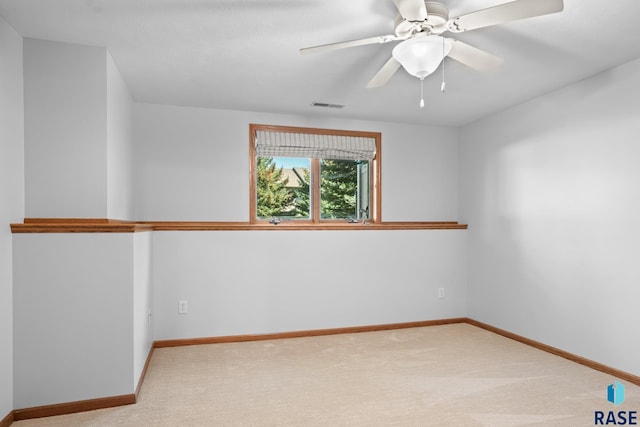 carpeted empty room with ceiling fan, visible vents, and baseboards