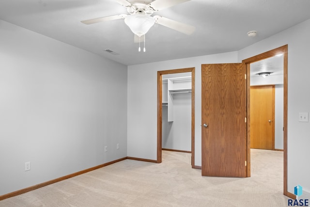 unfurnished bedroom with ceiling fan, light colored carpet, visible vents, baseboards, and a spacious closet