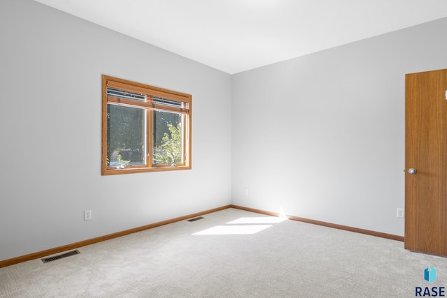 carpeted spare room featuring baseboards and visible vents