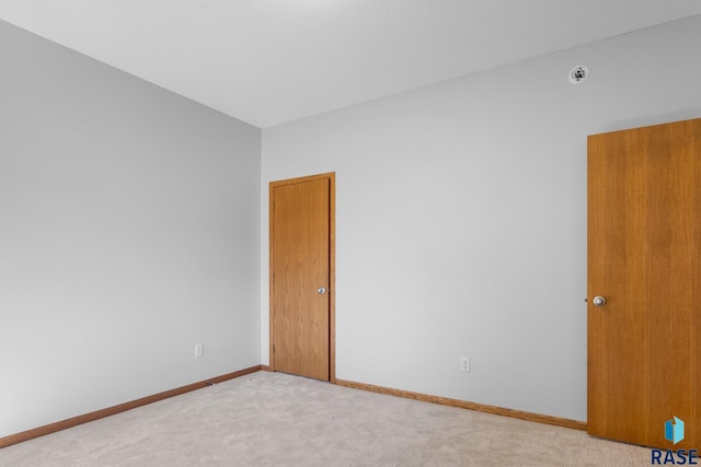 unfurnished room featuring baseboards and light colored carpet