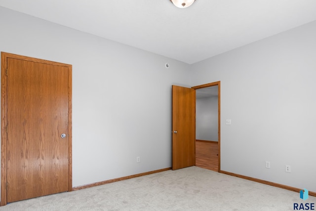 unfurnished bedroom featuring baseboards and light colored carpet