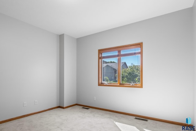 empty room featuring carpet floors, visible vents, and baseboards