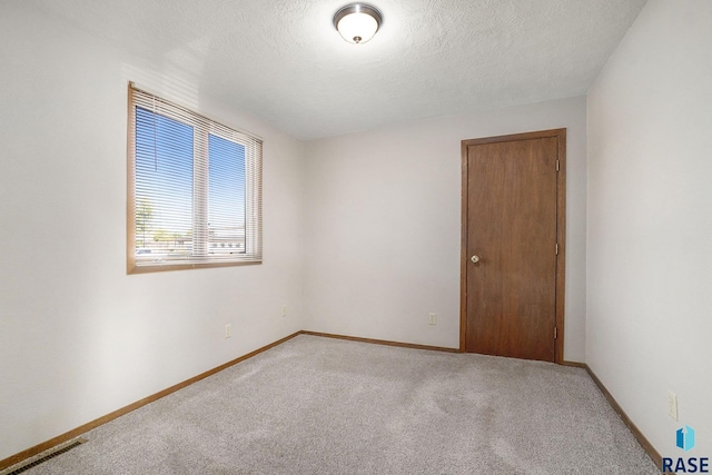 1512 W 7th St, Sioux Falls, SD 57104 - unfurnished room featuring visible vents, baseboards, light carpet, and a textured ceiling