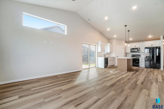 kitchen featuring pendant lighting, light hardwood / wood-style floors, a center island, white cabinets, and black appliances