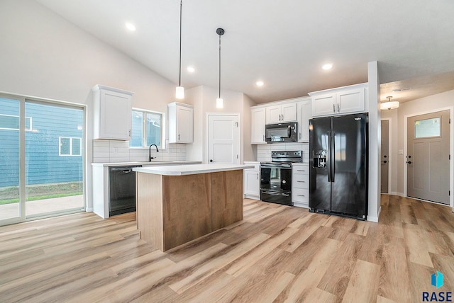 kitchen featuring white cabinets, a kitchen island, decorative light fixtures, and black appliances