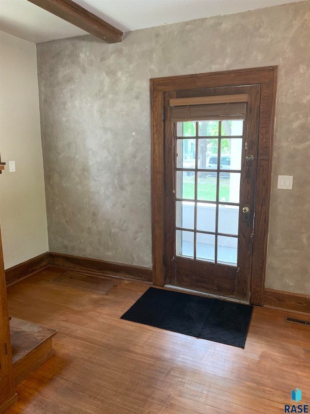 entryway with light hardwood / wood-style floors and beam ceiling